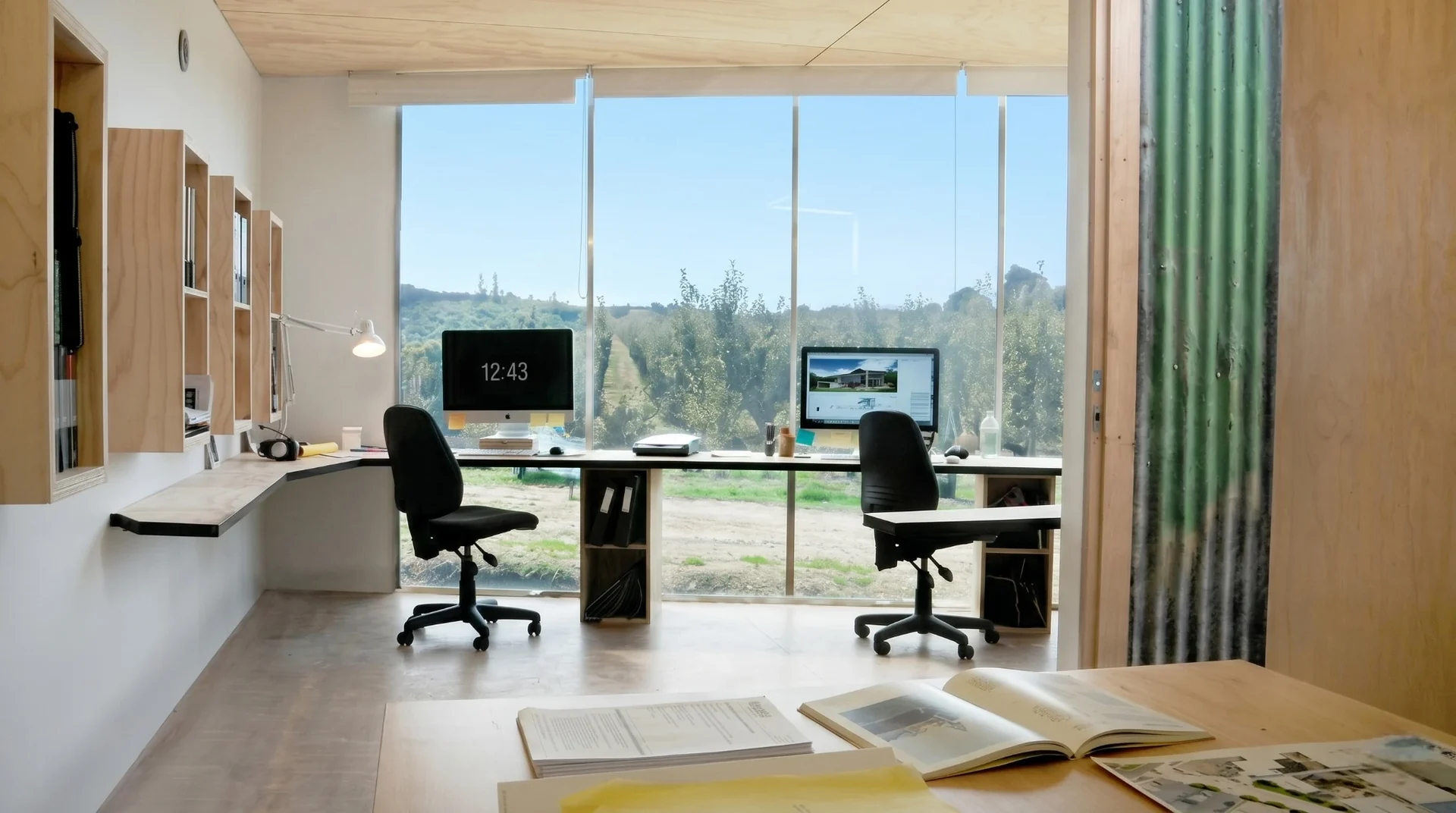Bright office studio with window desks, wood shelving, and a landscape view.